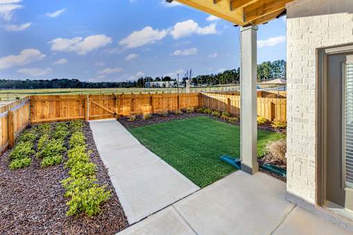 A backyard with a wooden fence and a green lawn.