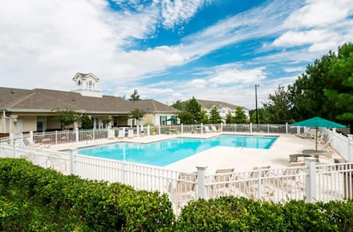 A pool surrounded by a white fence and green bushes. at The Dawson Cartersville in Cartersville, GA 30191