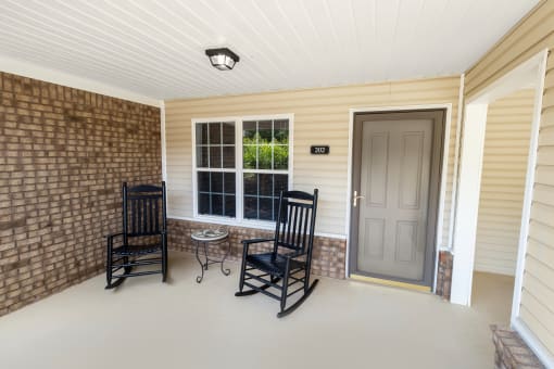 a front porch with rocking chairs and a small table