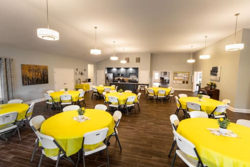 a large dining room with yellow table cloths and white chairs