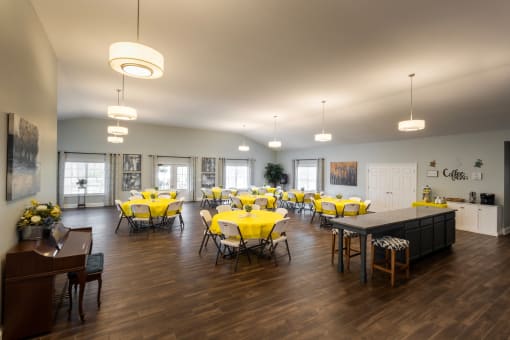 a large room with tables and chairs with yellow table cloths