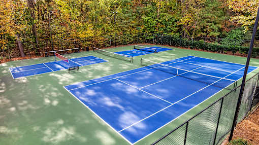A tennis court surrounded by trees in autumn.
