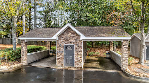 a covered parking lot with a small building with a door