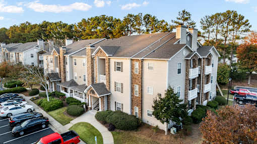 A large apartment complex with a parking lot in front.