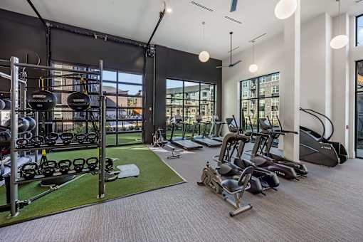 A gym with a variety of equipment including treadmills, weights, and exercise machines.