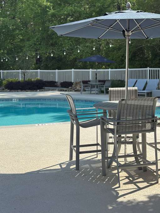 A poolside table with chairs and an umbrella.