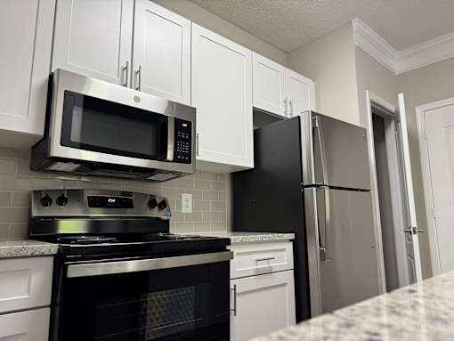 A kitchen with a black stove top oven and a black microwave above it.