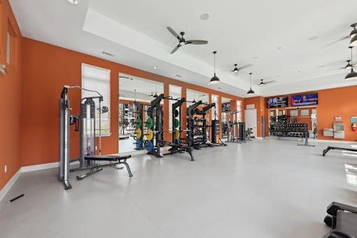 A gym with orange walls and a variety of exercise equipment.