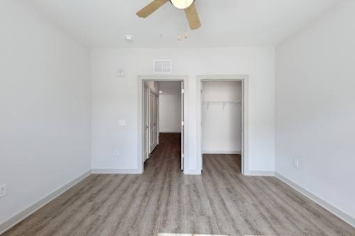 A room with a ceiling fan and two open doors.