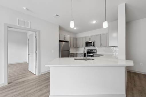 A white kitchen with a sink and a refrigerator.
