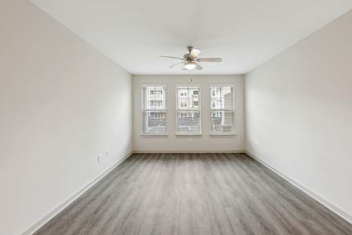 A room with a ceiling fan and a window with blinds.