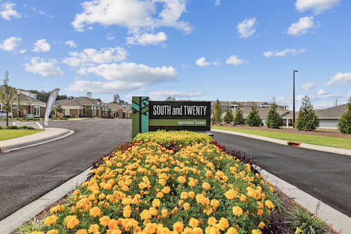 A sign that says South and Twenty in front of a flower bed.