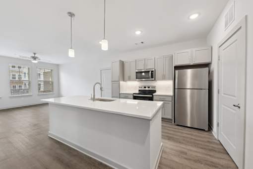 A modern kitchen with a white countertop and stainless steel appliances.