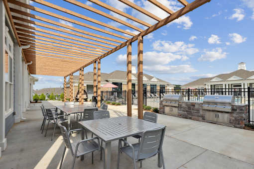 A patio with a table and chairs under a wooden pergola.