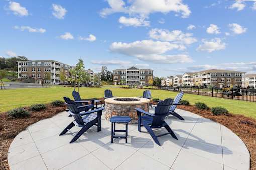 A fire pit surrounded by four chairs in a courtyard.