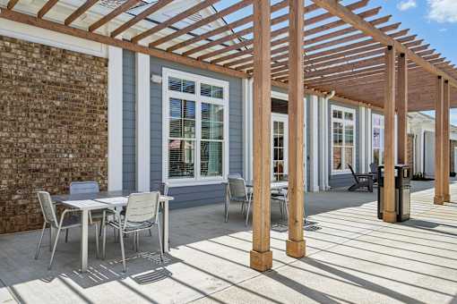 A patio with a table and chairs under a wooden pergola.