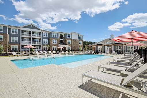 A pool area with sun loungers and a striped awning.