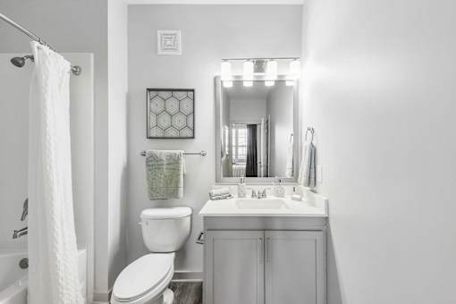 A white bathroom with a toilet, sink, and mirror.
