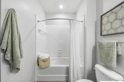 A white bathroom with a towel hanging on the wall.