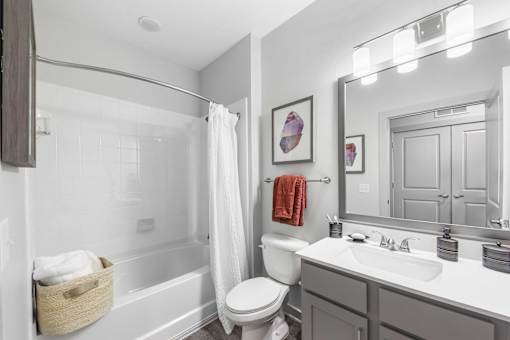 A white bathroom with a toilet, sink, and mirror.