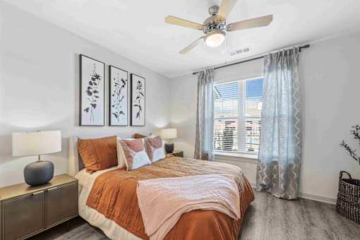 A bedroom with a bed, nightstand, and pictures on the wall.