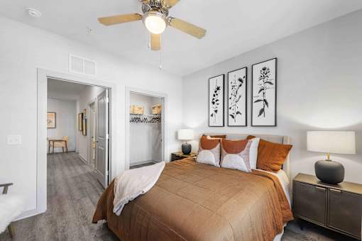 A bedroom with a bed, a ceiling fan, and a nightstand with a lamp.