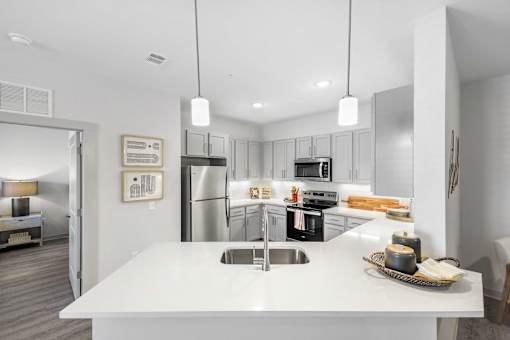 A modern kitchen with a white countertop and stainless steel appliances.