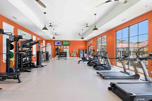 A gym with orange walls and a variety of exercise equipment.