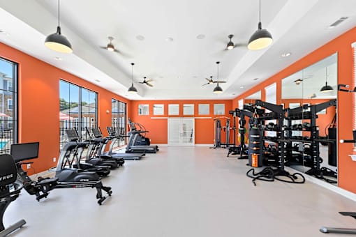 A gym with orange walls and a variety of exercise equipment.