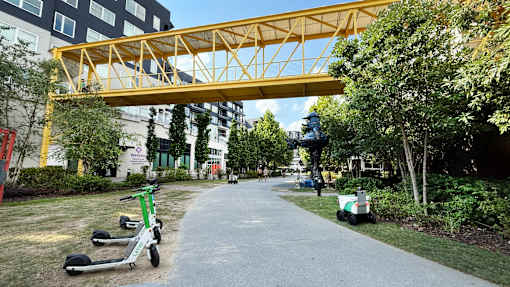 A yellow pedestrian bridge over a walkway with green scooters parked on the side. at West Inman Lofts, Georgia