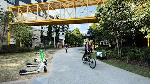A person riding a bike under a yellow bridge in a park. at West Inman Lofts, Atlanta, Georgia