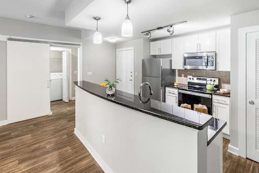 A modern kitchen with a white island and stainless steel appliances. at West Inman Lofts, Atlanta