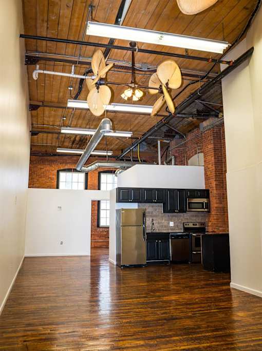 A kitchen with a brick wall and wooden floors.