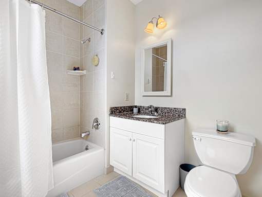 A white bathroom with a toilet, sink, and shower.