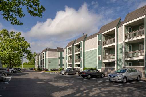 A parking lot with cars and apartment buildings.