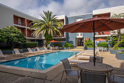 A pool area with chairs and an umbrella.