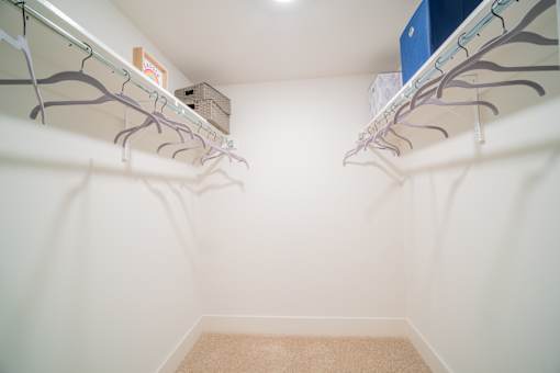 a walk in closet with two shelves and two hanging rails