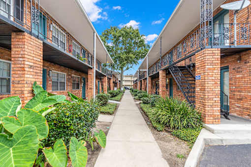 A long, narrow walkway separates rows of red brick apartment buildings.