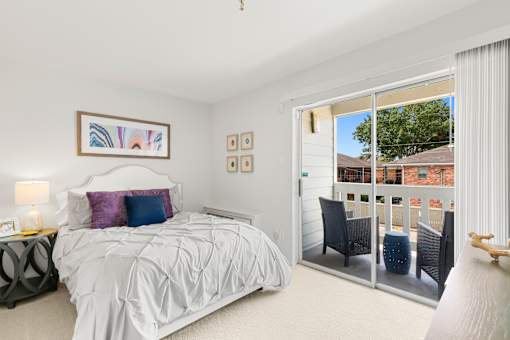 A bedroom with a large bed and a balcony.