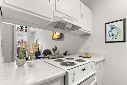 A white kitchen with a stove top oven and a fridge.