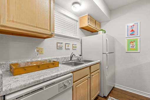 A kitchen with a white fridge, wooden cabinets, and a marble countertop.