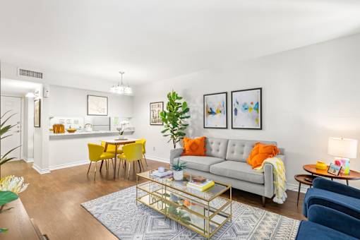 A living room with a grey couch, yellow chairs, and a glass coffee table.
