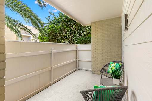 A balcony with a chair and a plant.