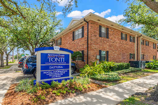 A brick building with a sign that says Apartment Homes TONTI Daytona Rental Information Center.