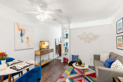 A living room with a white ceiling fan and a painting on the wall.