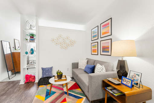 A living room with a grey couch, a coffee table, a lamp, and a bookshelf.