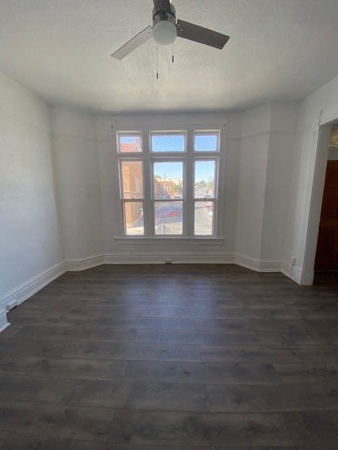 an empty room with a large window and a ceiling fan