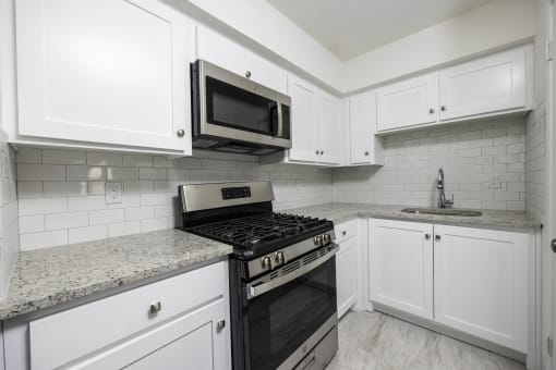 a kitchen with white cabinets and a stove and a microwave