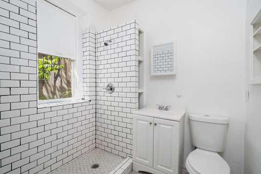 A white bathroom with a toilet and a shower.