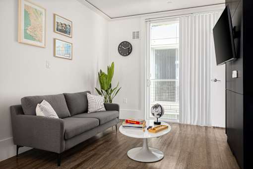 A grey couch with two pillows sits in a living room with a white coffee table in front of it.